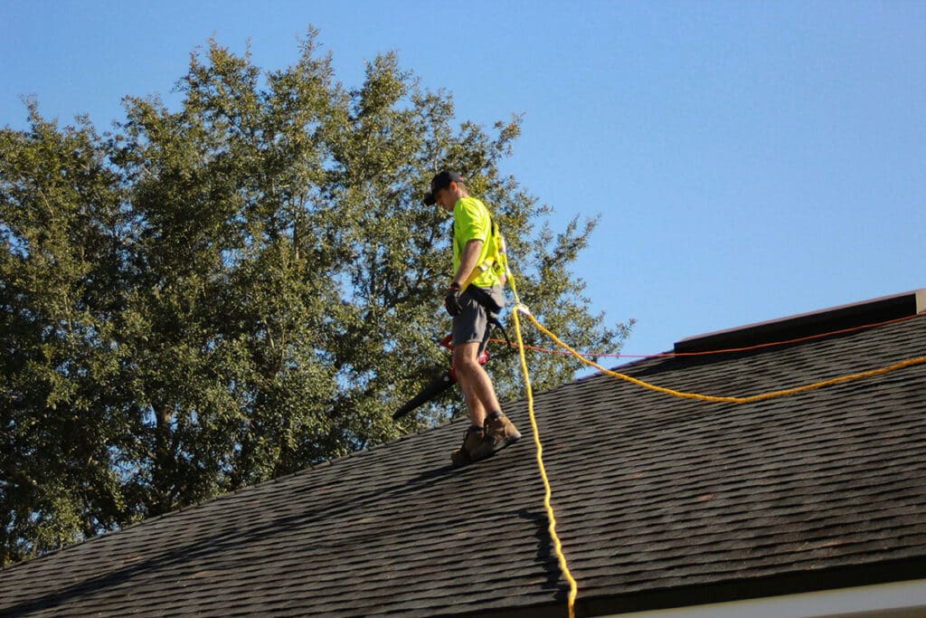 Roofer working safely on a sloped surface with fall protection gear, demonstrating effective project management.