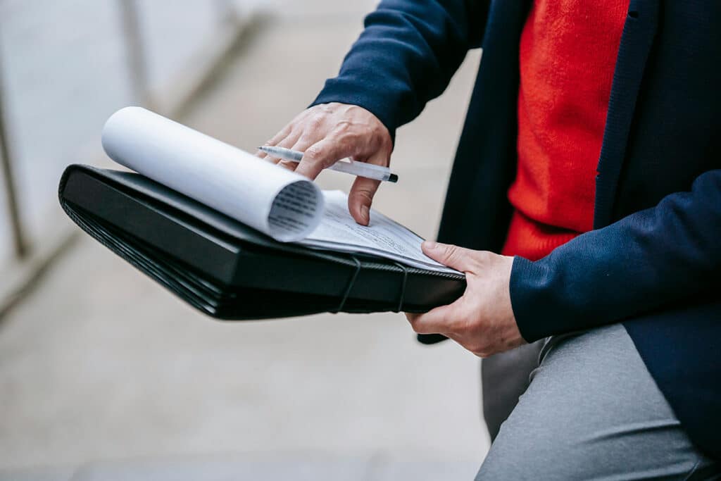 Person reviewing paperwork on a clipboard as part of field service management.