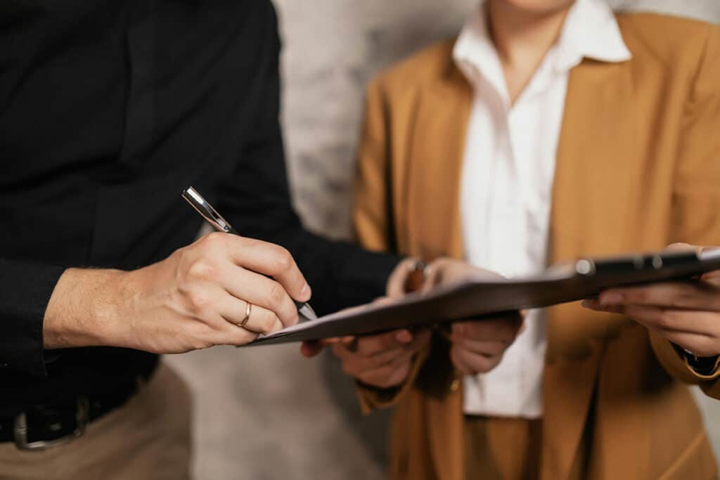 Contractor reviewing paperwork and signing roofing quotes on a clipboard during a job consultation.